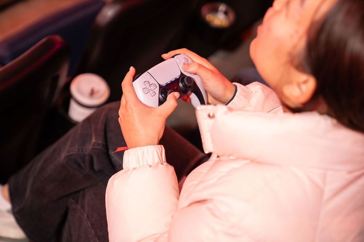 Person holding white gaming controller while sitting in orange lighting at an event