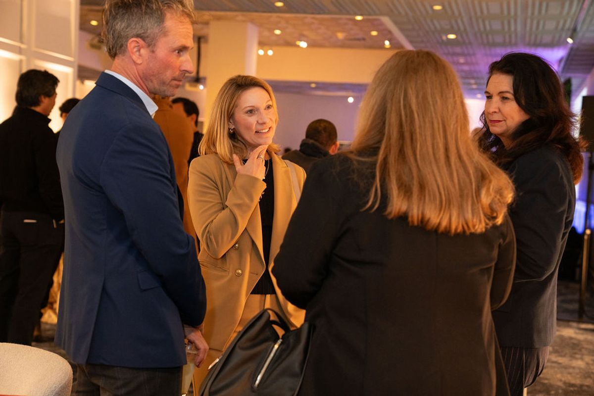Four business professionals having a conversation at a networking reception in an upscale venue with modern.