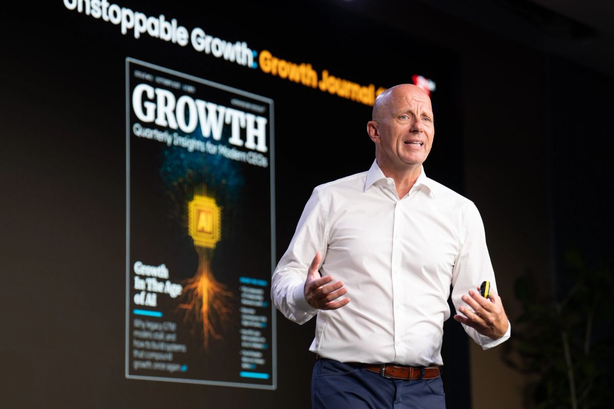Executive presenting on stage with "Unstoppable Growth" and magazine cover displayed on screen behind him