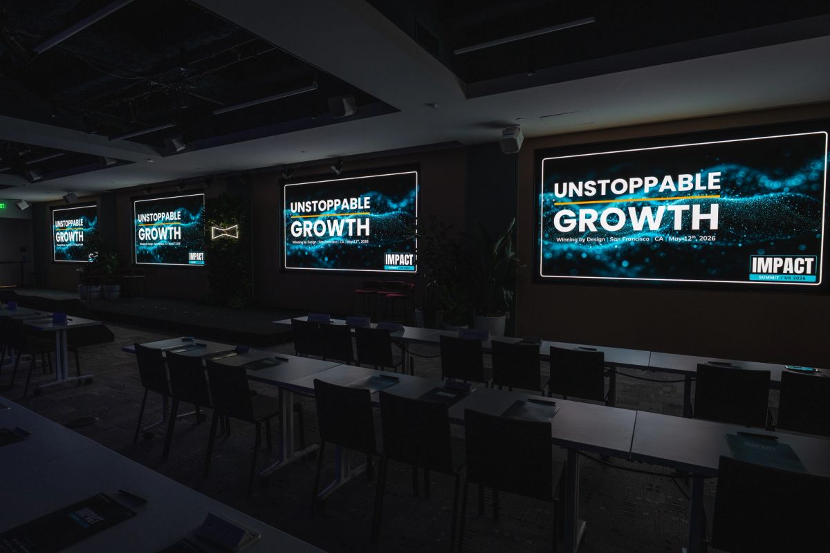 Conference room with multiple screens displaying Unstoppable Growth and Impact branding.