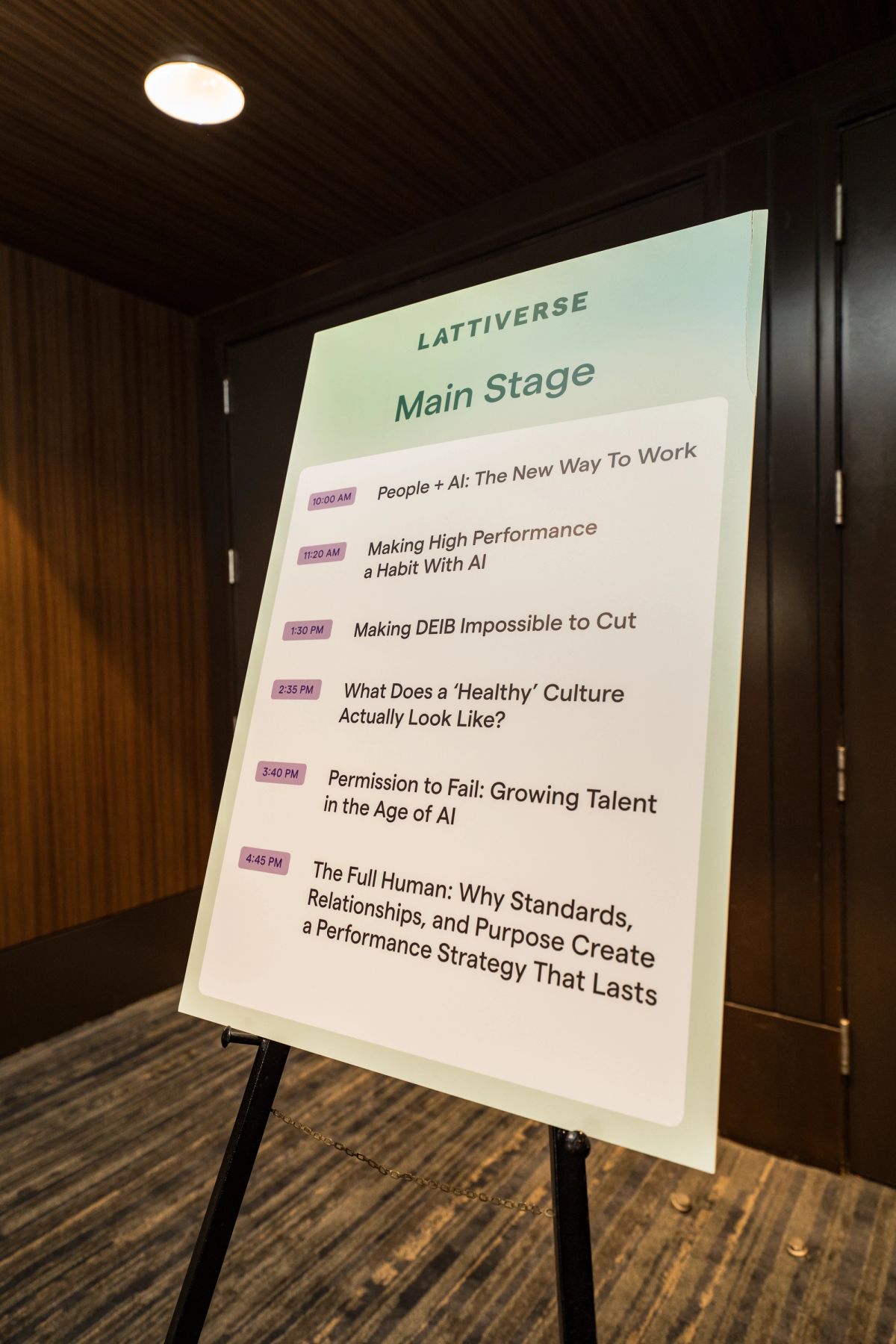 Lattiverse Main Stage schedule board on easel listing six sessions from 10AM to 4:45PM.