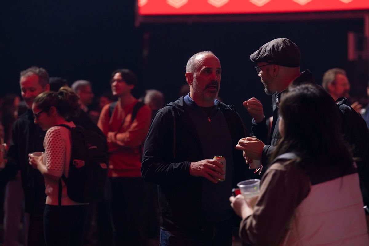 Conference attendees networking and conversing in a dimly lit venue with red lighting