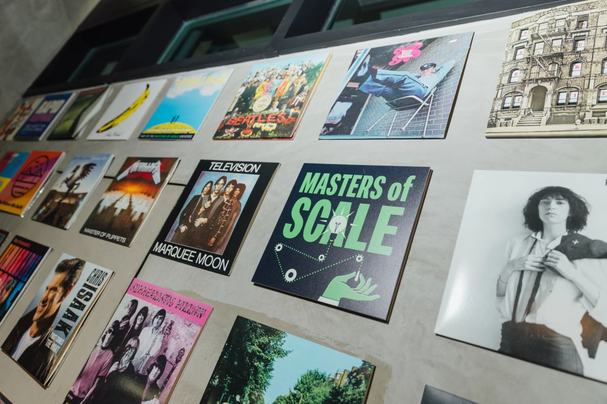 Display wall showing various album covers and music-related artwork including "Masters of Scale" poster