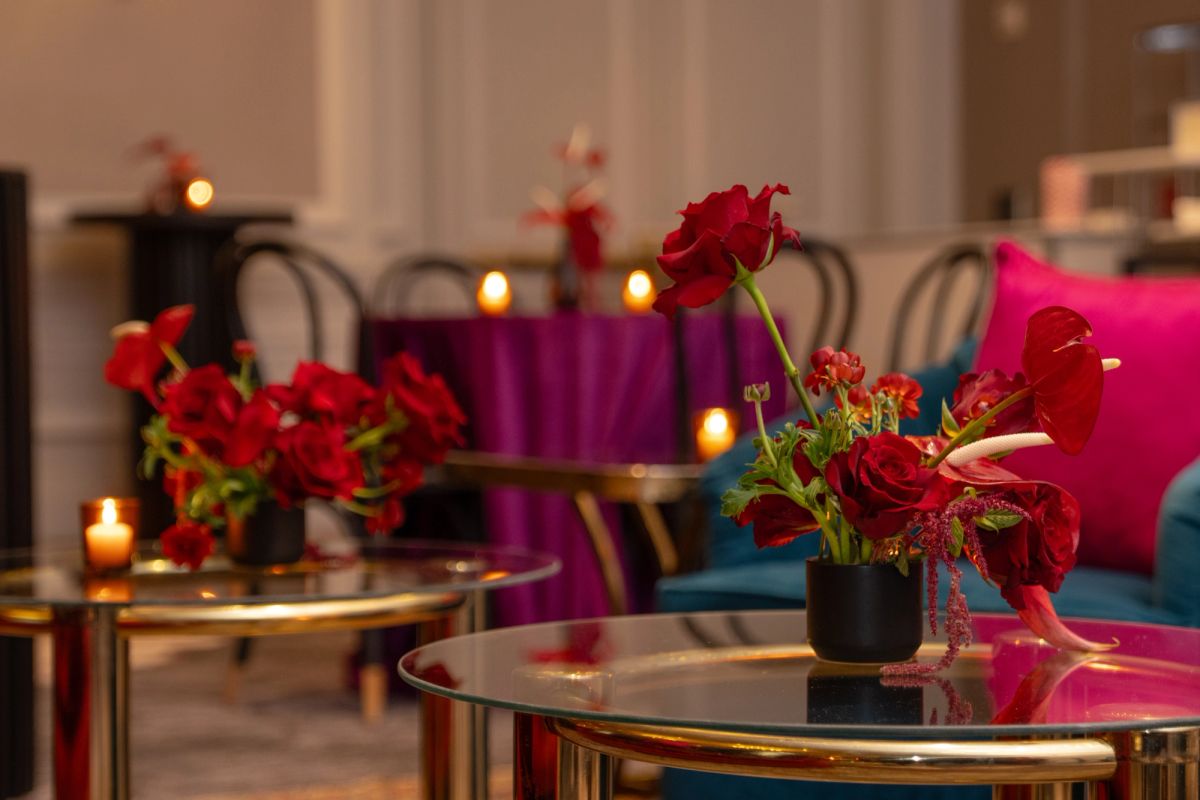 Round glass tables with red flower arrangements and candles in an elegant lounge with colorful chairs