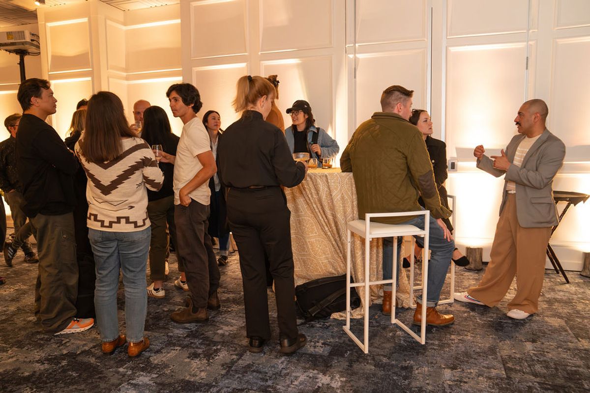 People networking at a reception in a modern white interior space with illuminated wall panels
