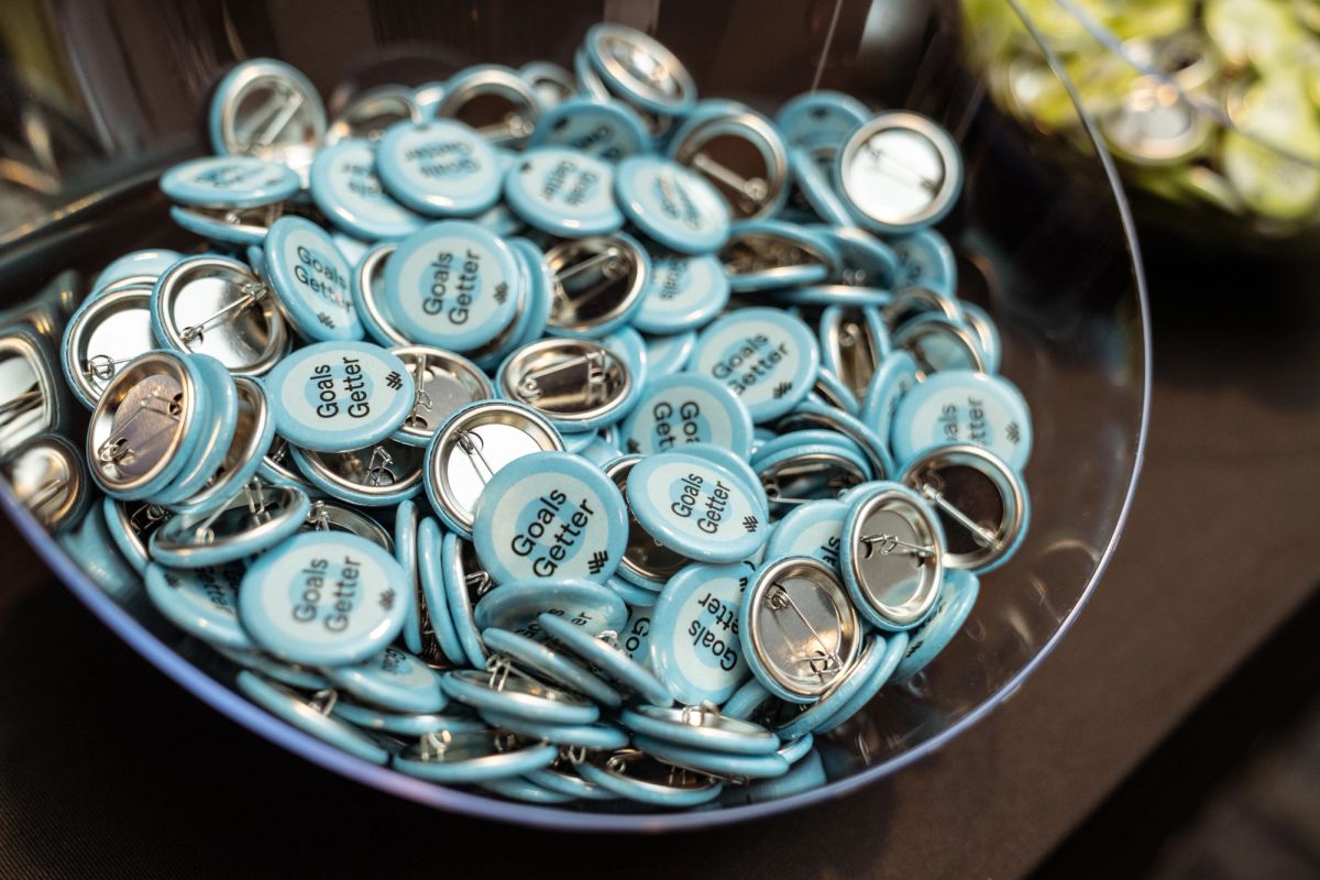 Light blue "Goals Getter" pins piled in a clear bowl at a conference.