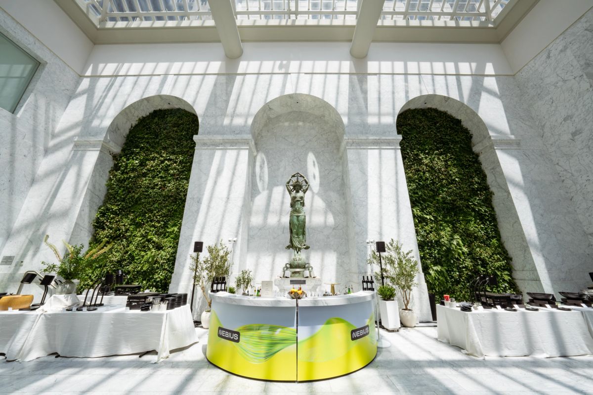 Nebius branded circular bar in a sunlit atrium with living walls and a bronze statue.