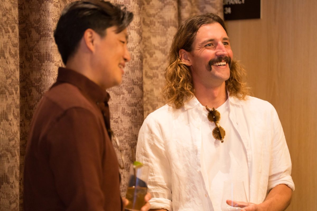 Two speakers conversing and smiling during a panel discussion in a venue with exposed brick walls