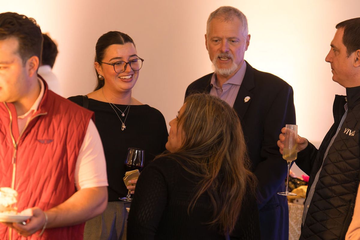 People networking and socializing with drinks at an indoor reception event.