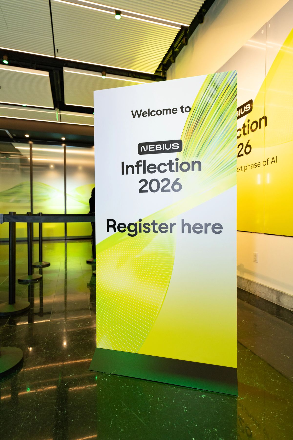 Registration sign for Nebius Inflection 2026 event in a modern lobby with yellow-green branding.