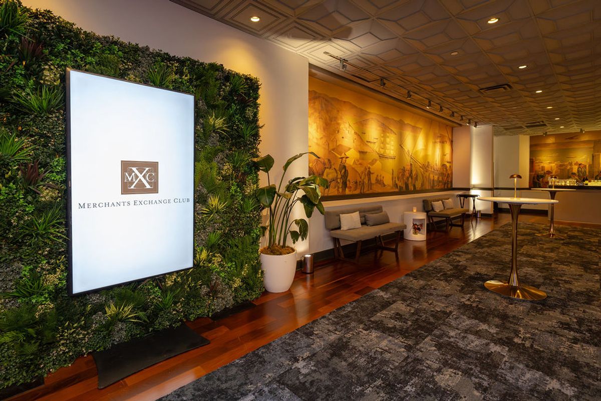 Modern lobby with living wall, MXC Merchants Exchange Club sign, seating area, and reception desk