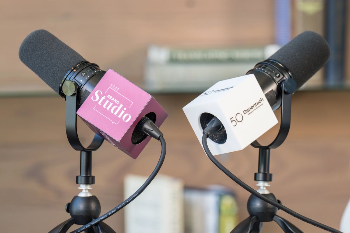 Two microphones with pink and white branded covers positioned for an interview or panel discussion