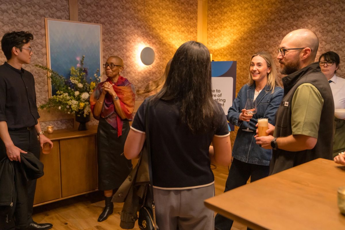 People networking and socializing in a warmly lit room with decorative wallpaper and modern lighting.