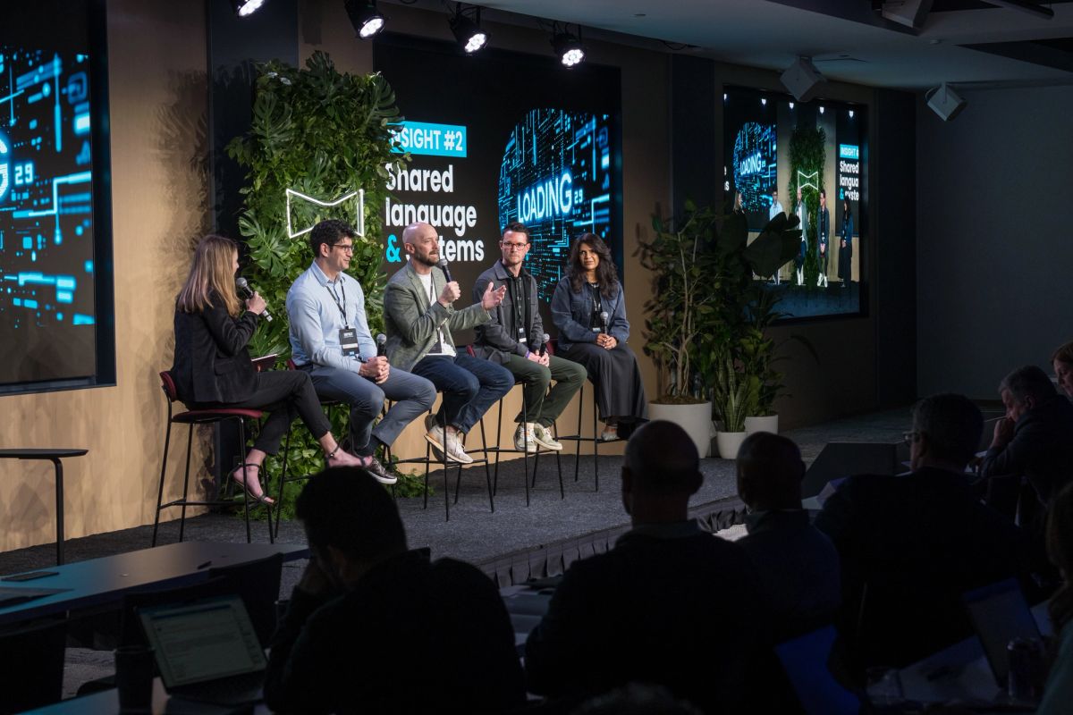 Panel discussion with five speakers on stage in front of audience at tech conference venue