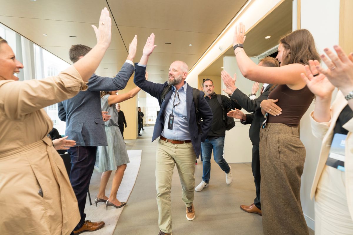 Business professionals celebrating with high-fives in modern office lobby during corporate event