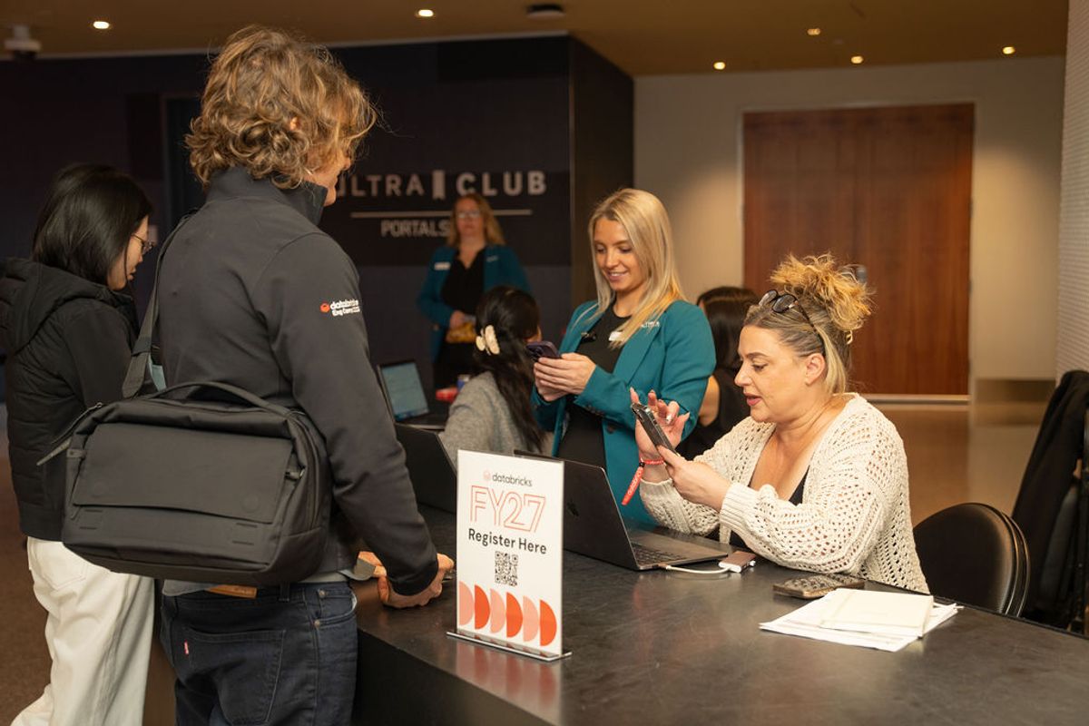 People registering at event check-in table with "FY27 Register Here" sign and Ultra Club backdrop visible