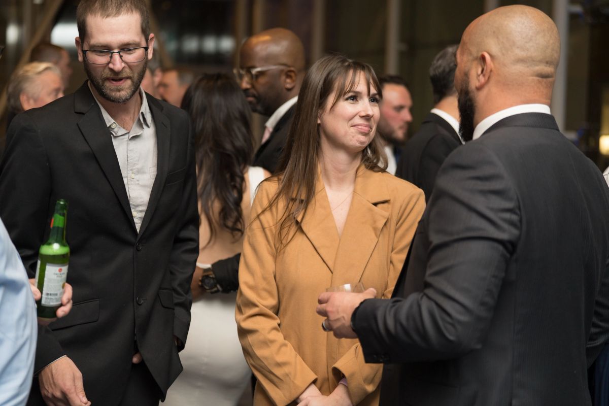 Attendees in business attire networking and conversing at an upscale indoor event venue.
