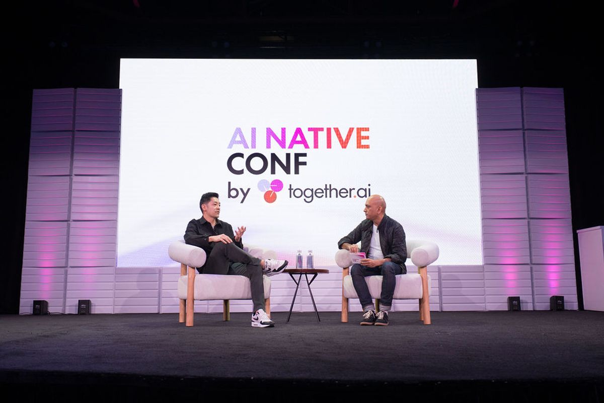 Two speakers in conversation on stage at AI Native Conf by together.ai, seated in white chairs with purple.