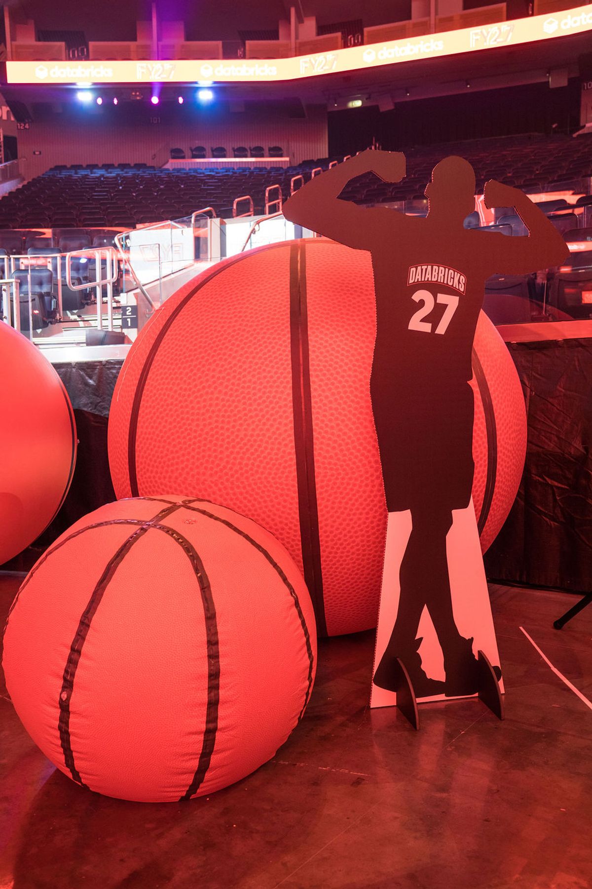 Person in Databricks jersey stands near large basketball props at indoor arena event