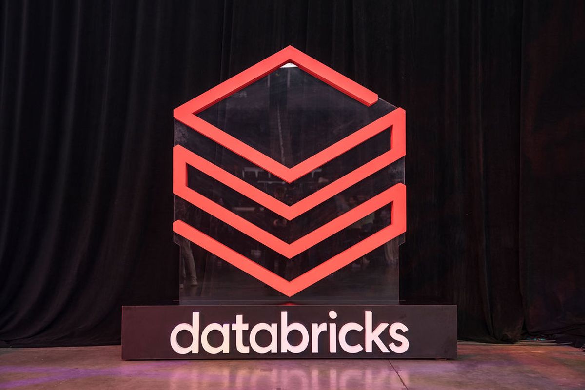 Illuminated red Databricks logo on stage with black curtain backdrop at conference venue