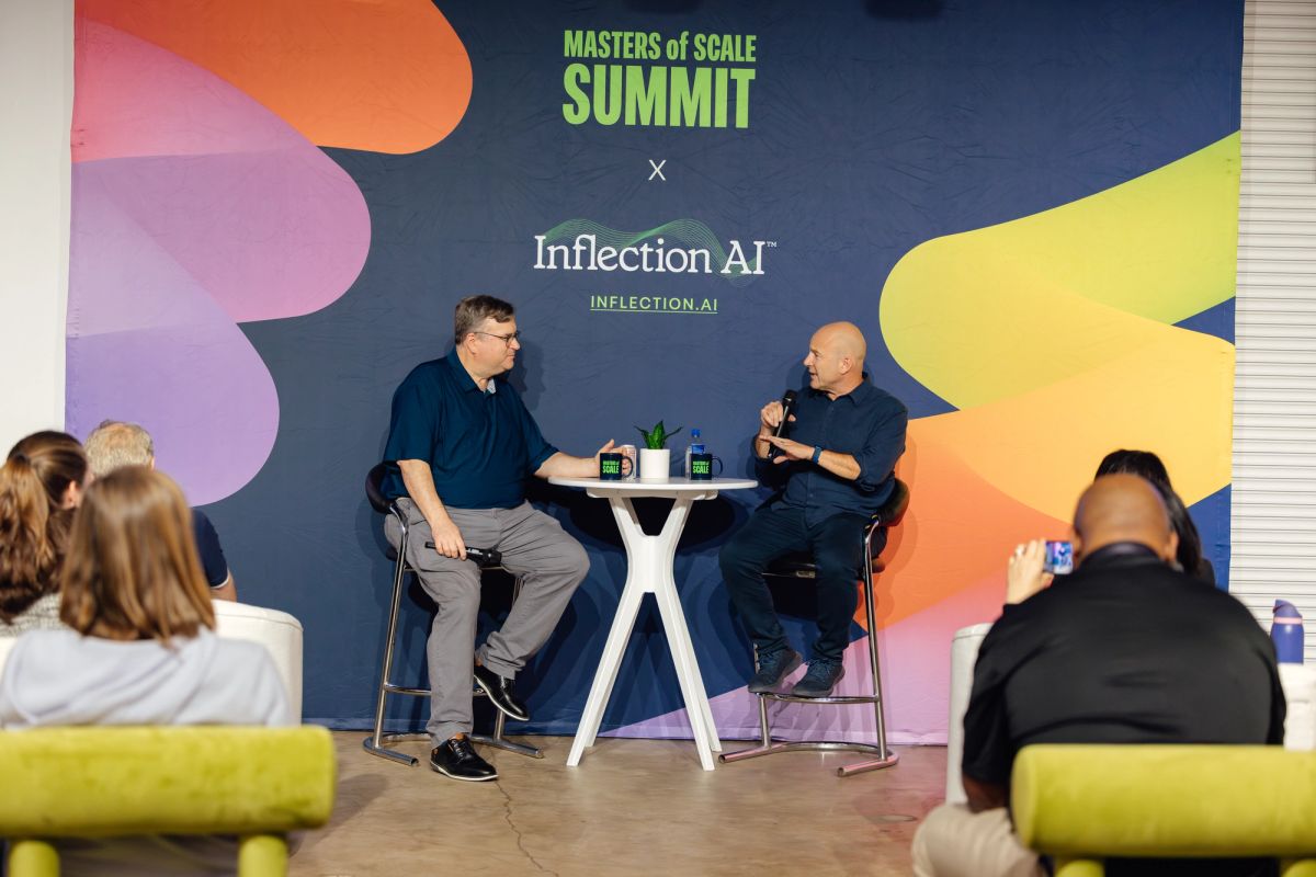 Two speakers in conversation on stage at Masters of Scale Summit x Inflection AI event, with audience seated.