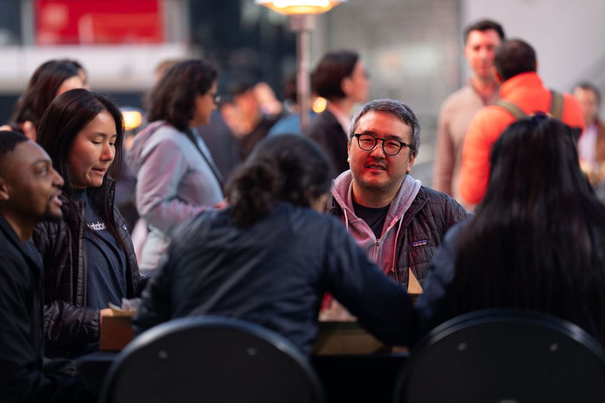 Attendees networking and socializing at a conference reception with people seated and standing in groups