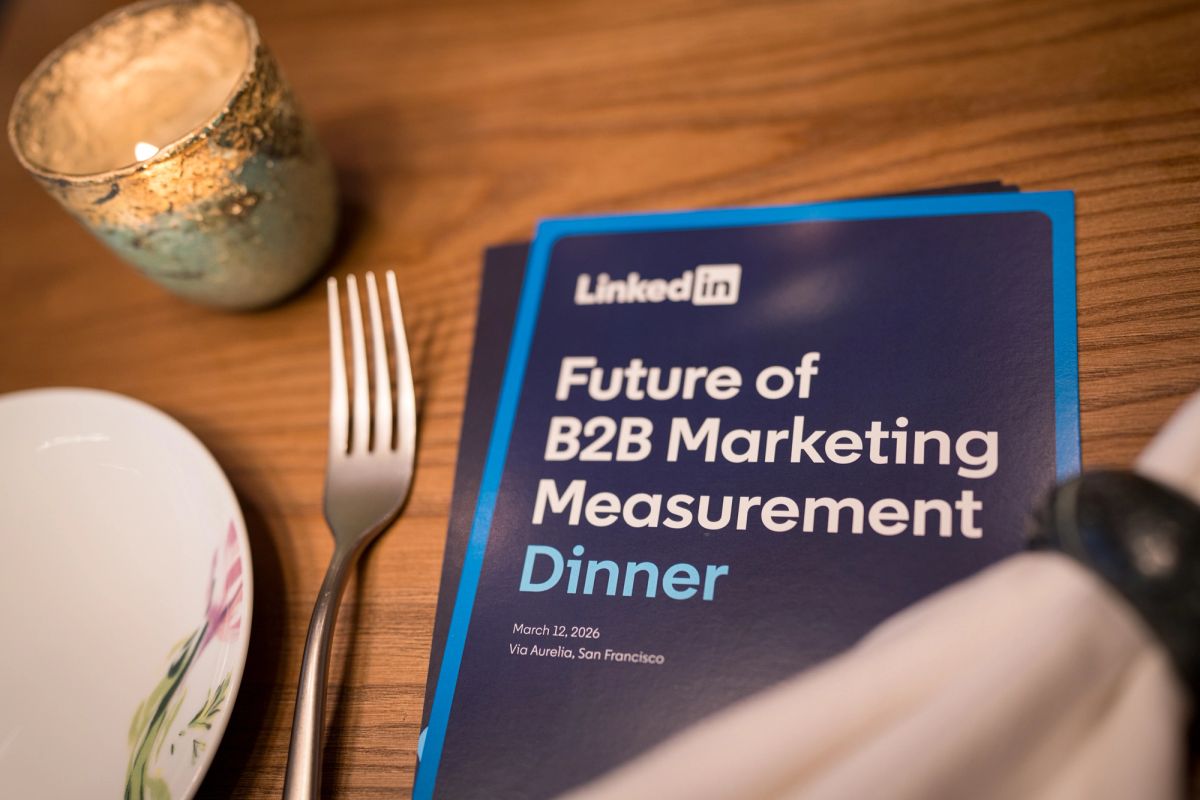 LinkedIn event program for "Future of B2B Marketing Measurement Dinner" on table with plate, fork and candle