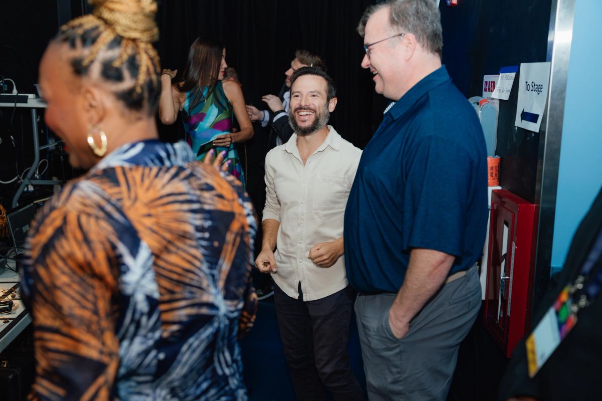 Attendees networking and conversing in a casual backstage or event space with equipment and materials visible
