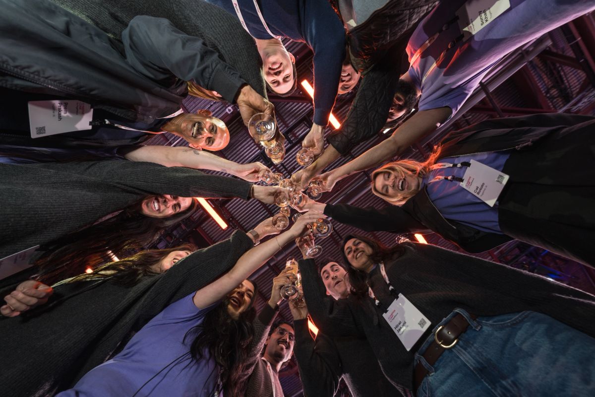 Group of conference attendees in business attire making a toast with wine glasses in a circle formation