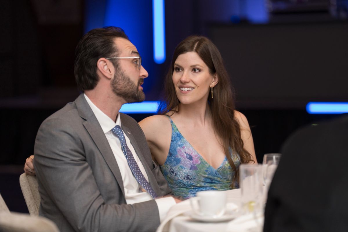 Man in suit and woman in blue dress sitting together at formal event table