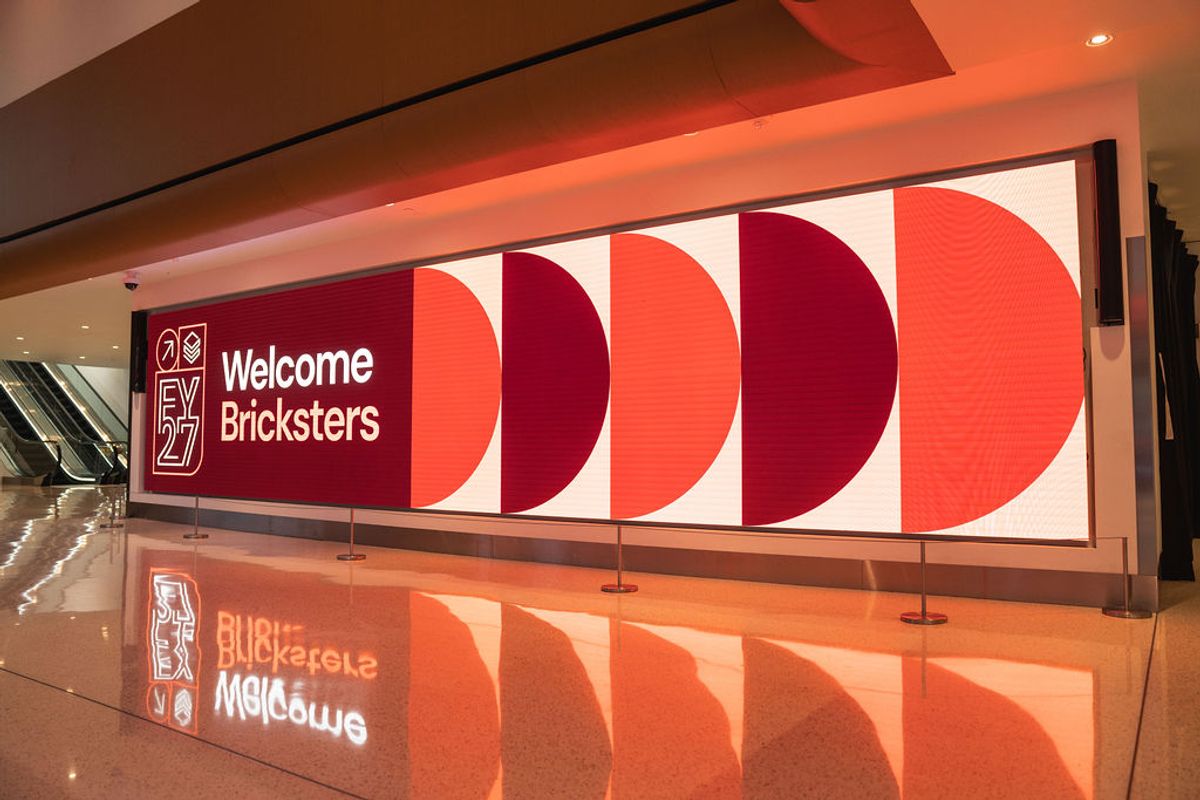 Large red and white wall display reading "Welcome Bricksters" with geometric circular design in modern venue.