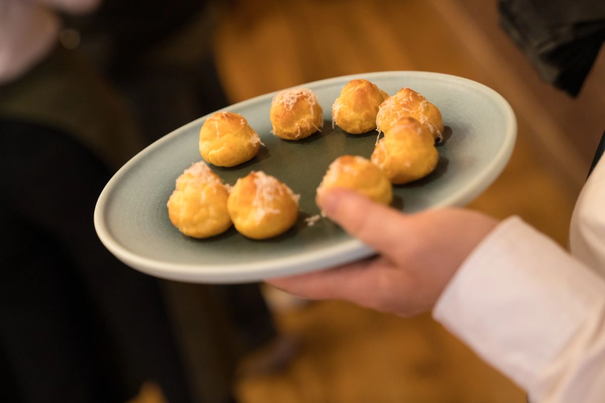 Person holding plate of golden pastries at indoor event
