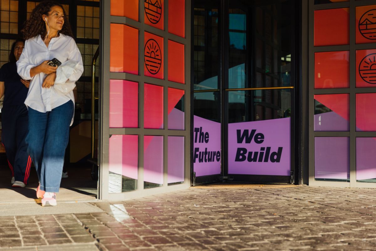 Woman walking past colorful storefront windows displaying "The Future We Build" text on gradient panels