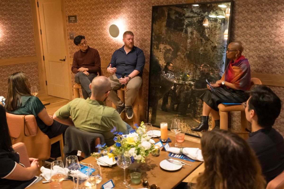Panel discussion with speakers seated around table and audience members in restaurant setting