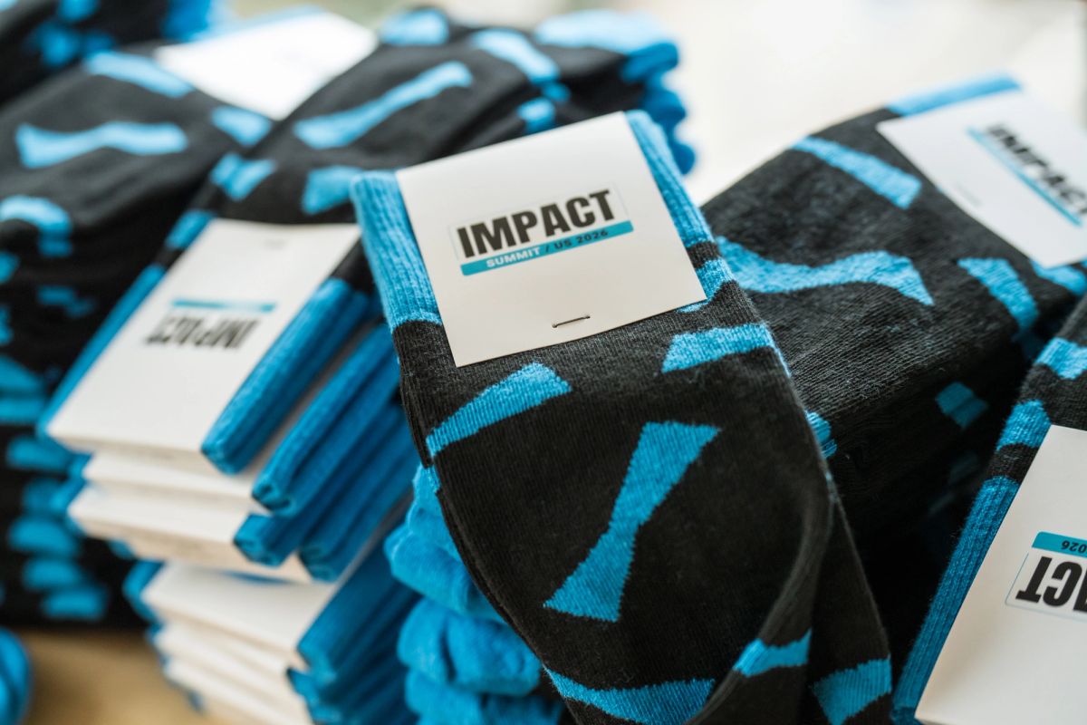 Stacks of black and blue patterned socks with white IMPACT labels at a conference event.
