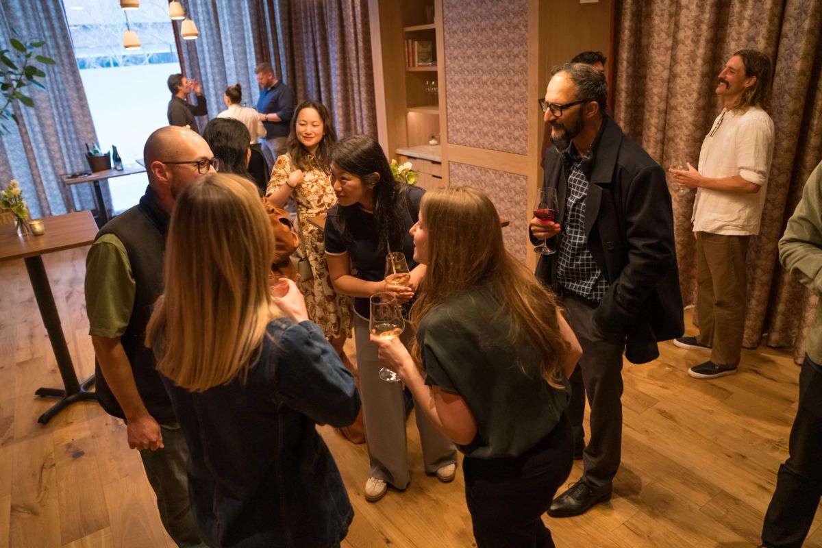 Attendees networking and conversing in small groups in an elegant indoor venue with curtained windows.