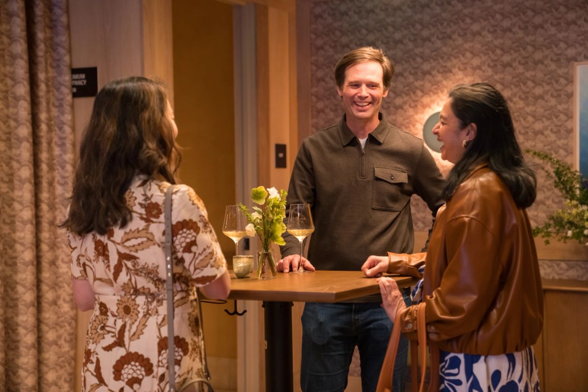 Three people networking in an upscale hotel lobby, with one person holding a wine glass during conversation