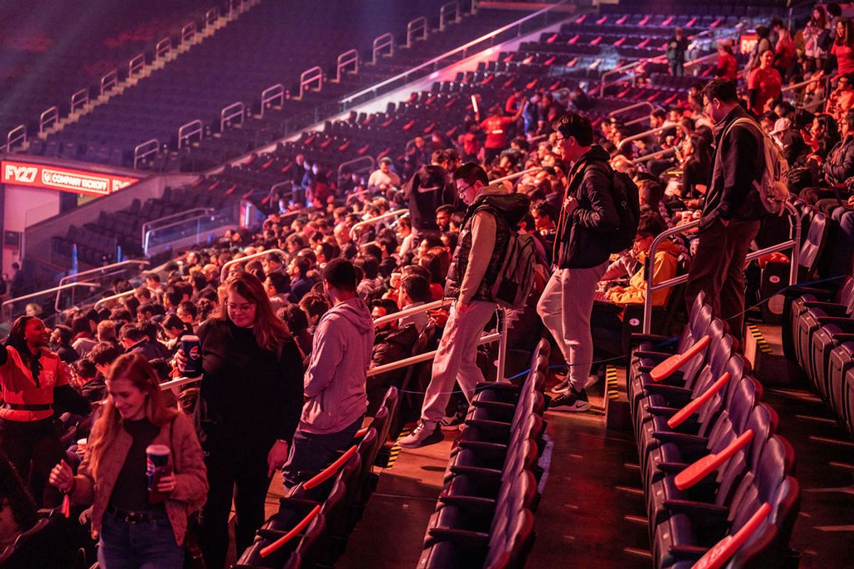 Attendees walking up arena stairs bathed in red and purple stage lighting at an indoor venue