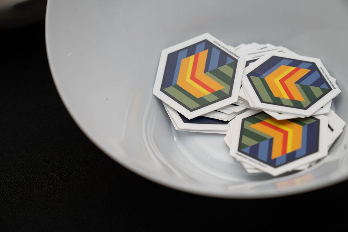 Hexagonal stickers with colorful geometric chevron patterns sit in a white bowl on a dark surface.