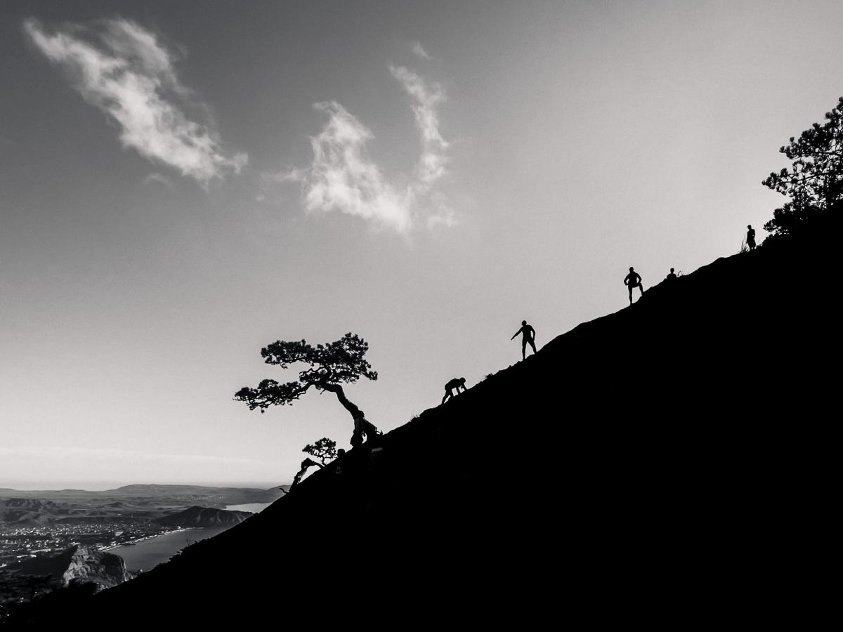 people in a row climbing a steep hill