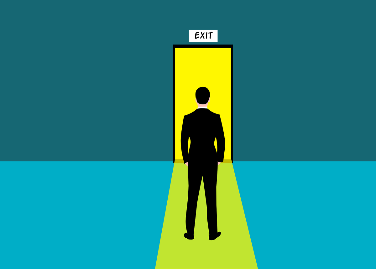 man standing infront of door with exit sign above