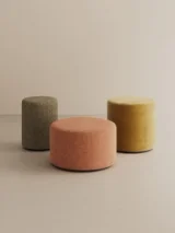 Three cylindrical beige upholstered poufs