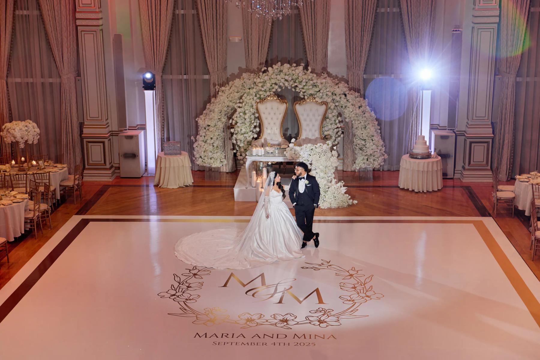 Bride and groom on a ballroom dance floor framed by florals.