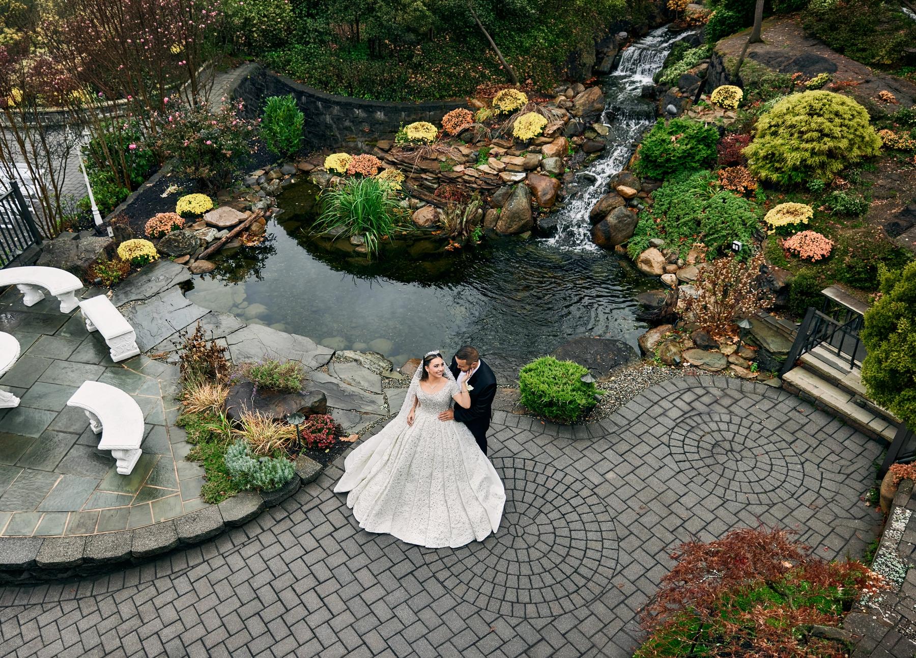 Couple embracing at night in front of a floral installation by the waterfront.