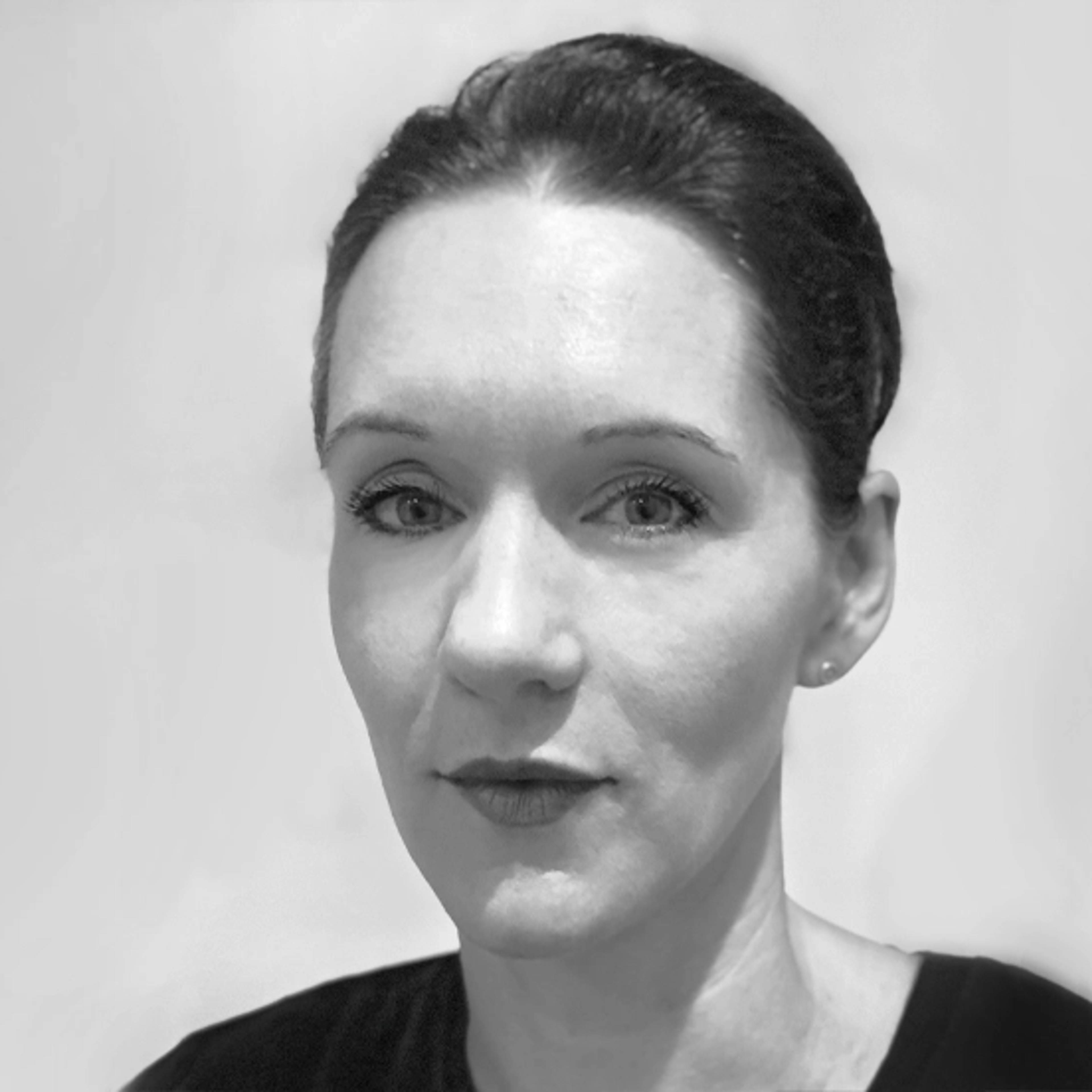 Black and white portrait of a woman with her hair pulled back, wearing a dark top against a plain light background. She is looking directly at the camera with a neutral expression.