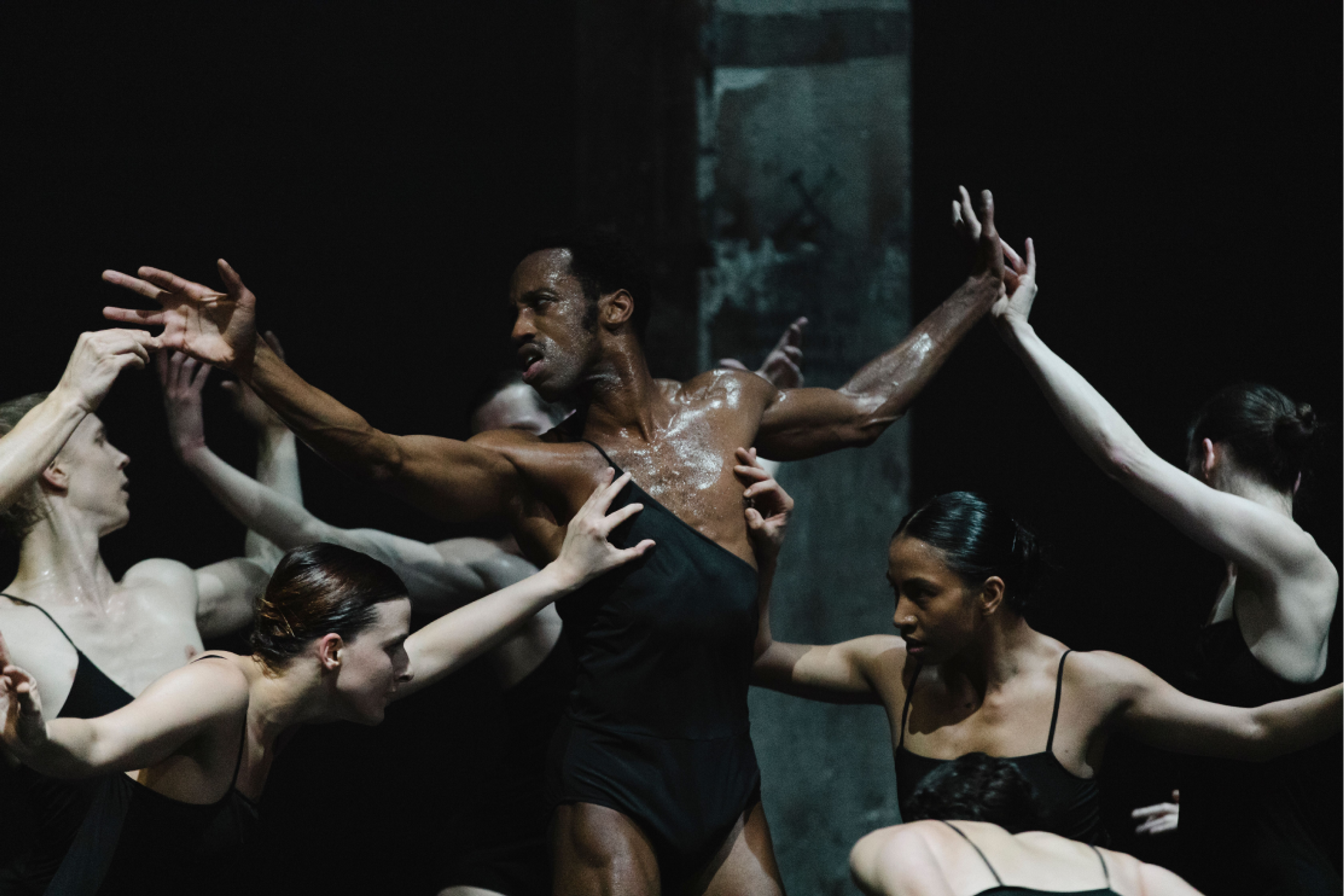 Male dancer with outstretched arms surrounded by group of female dancers in This Is Not a Love Show at Kraftwerk Berlin.