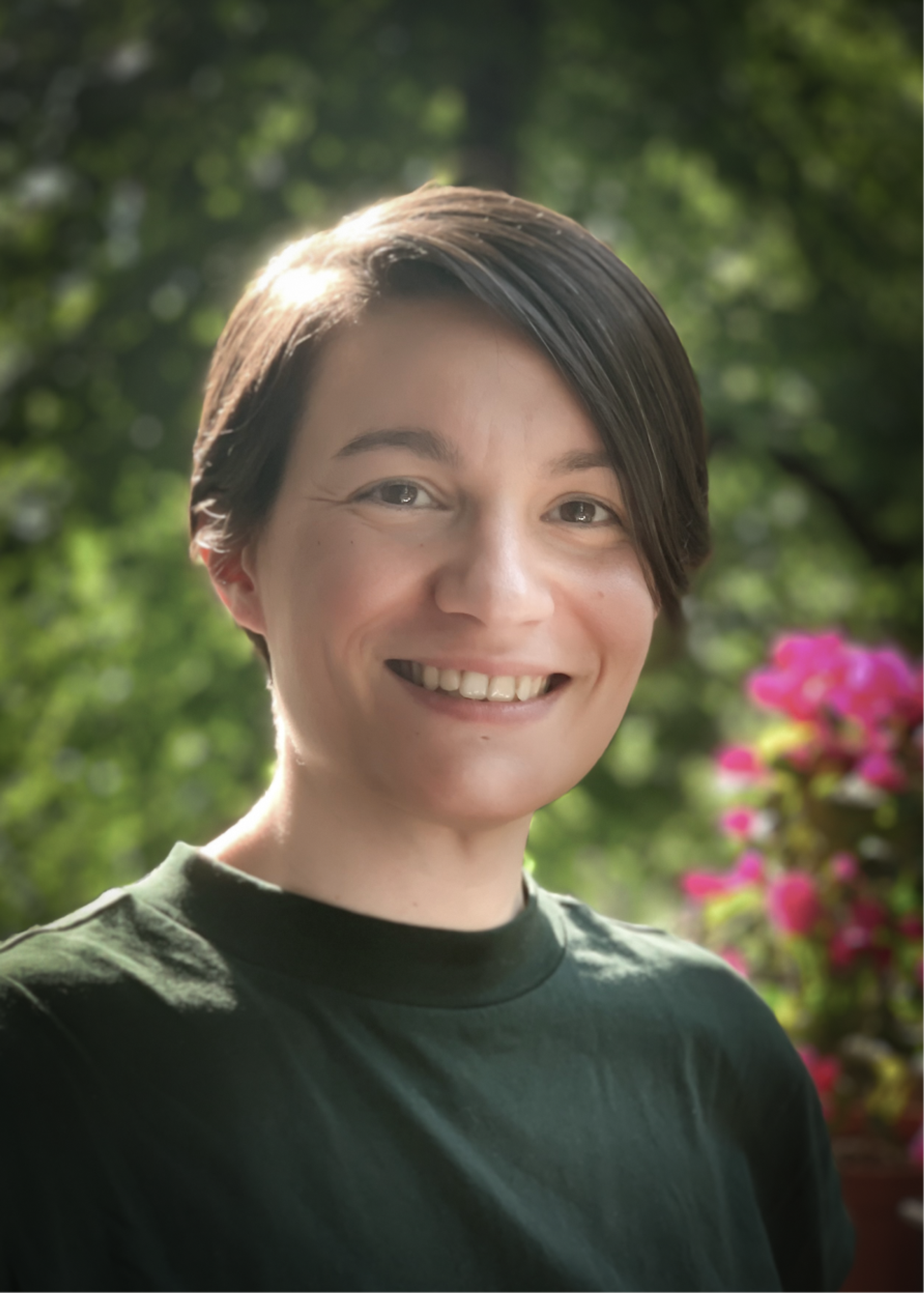 Portrait of quantum researcher Anna Pappa posed in a garden setting with pink flowers.
