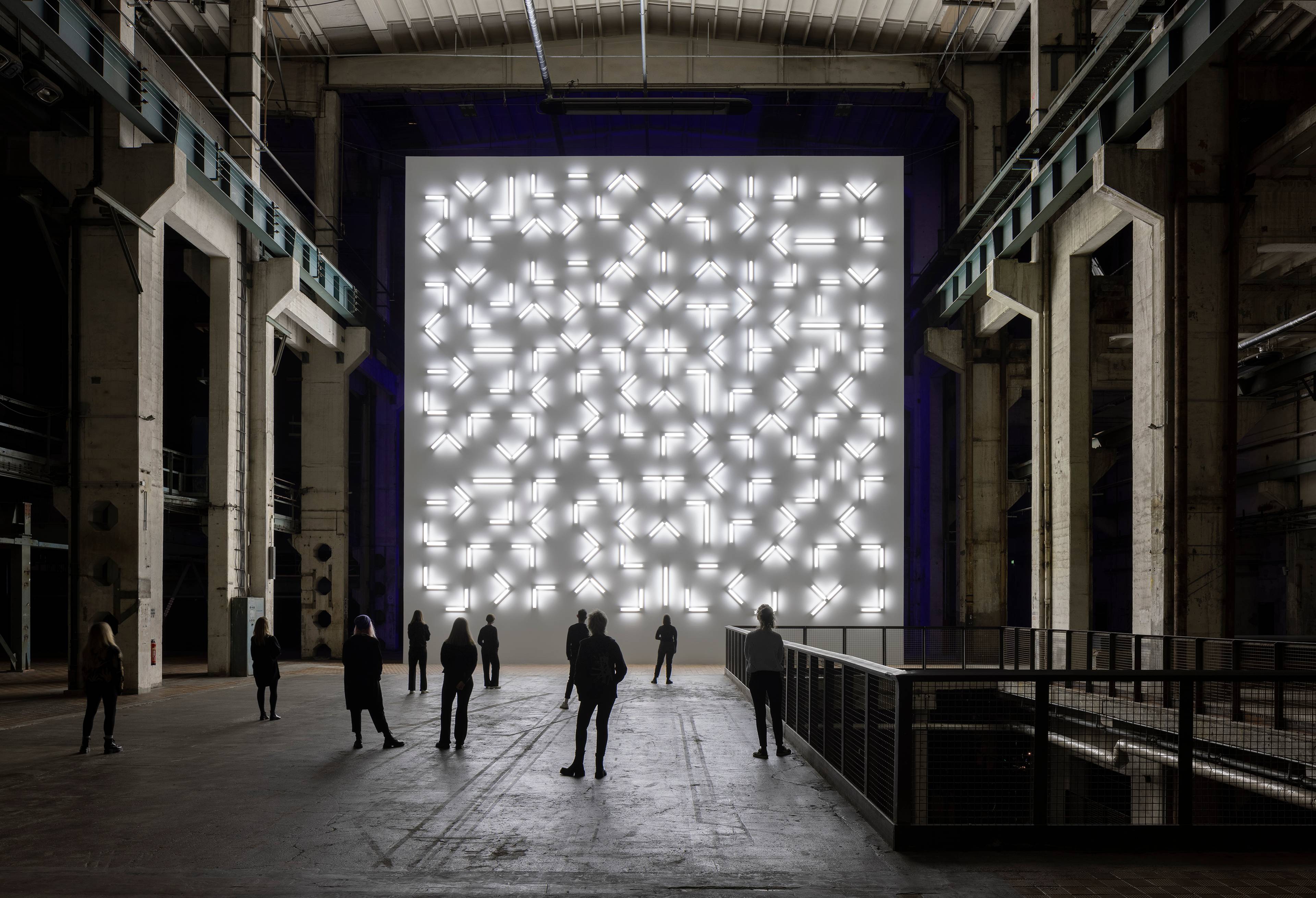 Weitwinkelbild von Menschen, die Robert Irwins Kunstwerk Licht und Raum im Kraftwerk Berlin betrachten