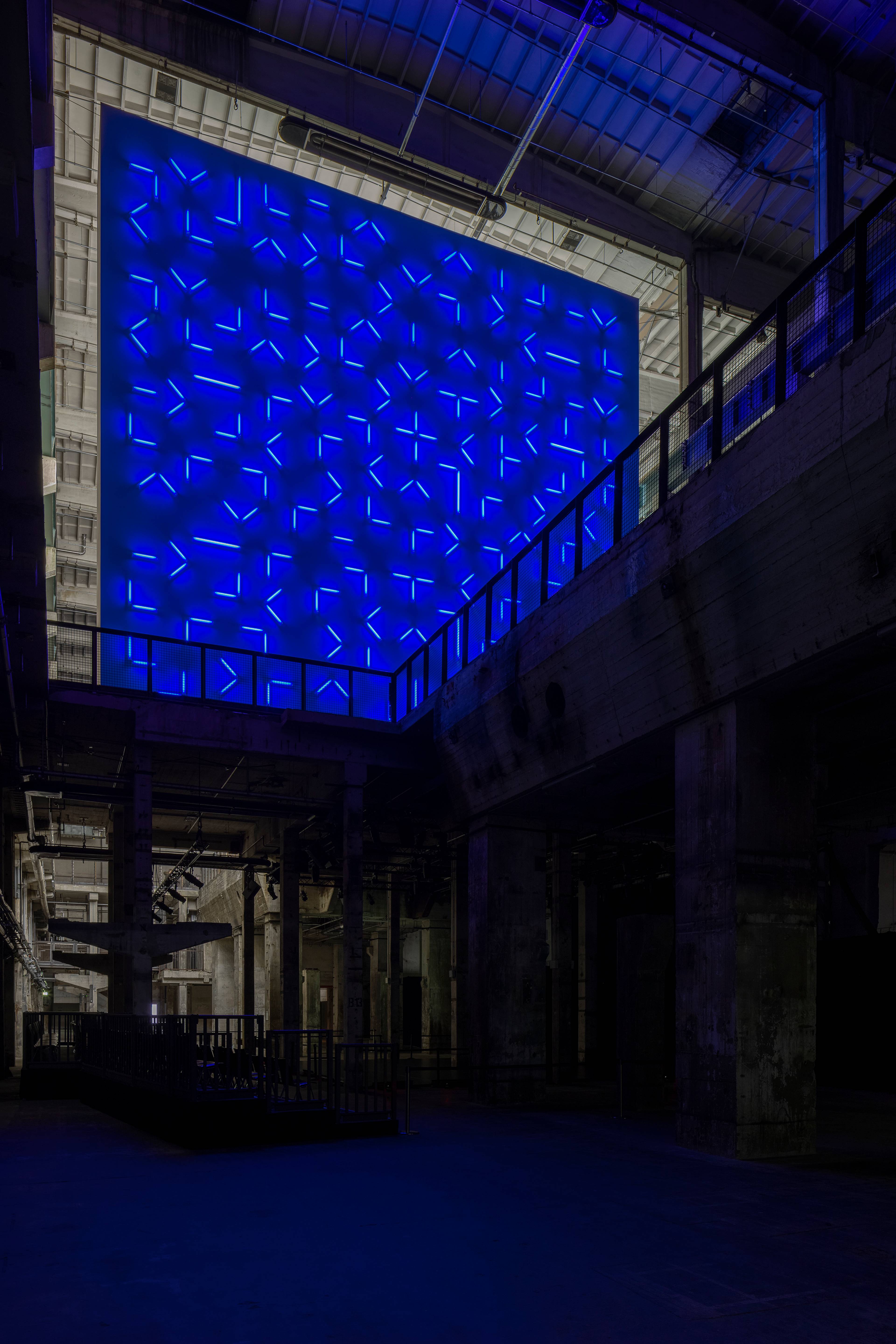 Blick nach oben auf eine große Wand aus bläulichen Leuchtstoffröhren im Kraftwerk Berlin