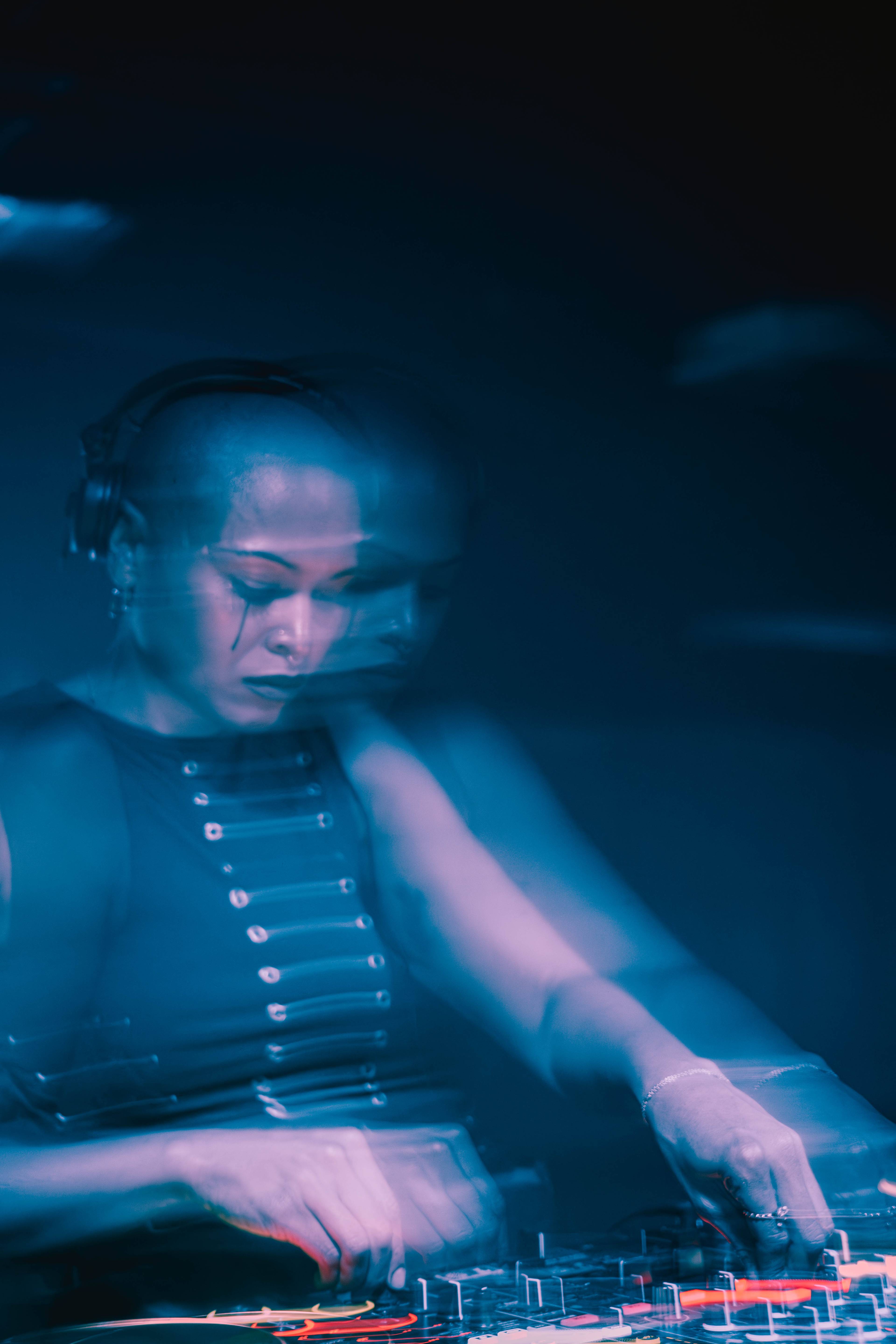 A DJ and rapper perform at a crowded indoor event, with the audience closely gathered around, enjoying the show.